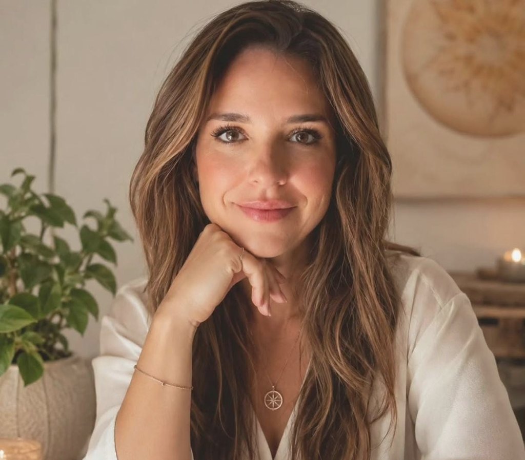 Retrato de Daniela Vivian sorrindo, com a mão apoiada no queixo, em luz suave